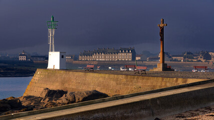 Calvary and lighthouse in the evening during a clearing at the entrance to the port of Barfleur, a commune in the peninsula of Cotentin in the Manche department in Lower Normandy in France