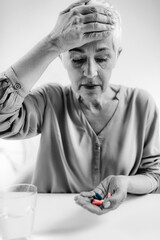 Senior Woman with Migraine Headache Holding Pills