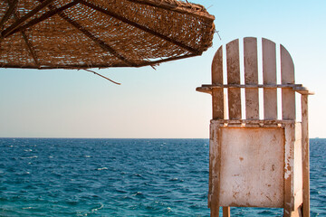 umbrella and white wooden chair on the background of blue sky and red sea, Hurghada, Egypt