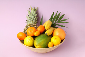 Bowl with exotic fruits on pink background