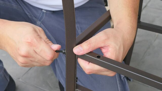Man doing DIY assembly steel chair frame furniture interia decoration 