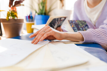 Young white woman working with sketchbook while sitting indoors