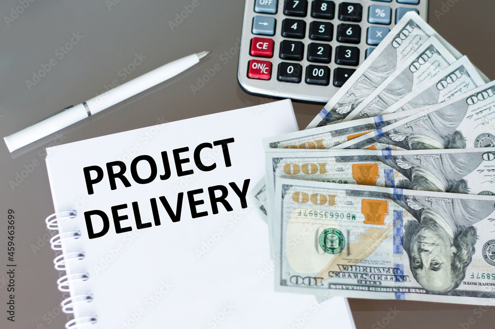 Aufkleber business concept. notebook with text project delivery on the table next to a calculator and money