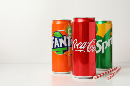 Odessa, Ukraine - September 23, 2021: Coca - Cola, Sprite and Fanta cans, and straws on white table