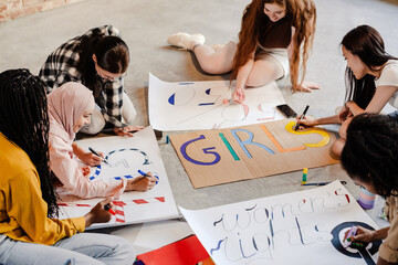 Multiracial young feminist women making posters during meeting
