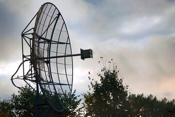 Military radar or radio telescope, silhouette of antenna against evening sky. Space observatory or...