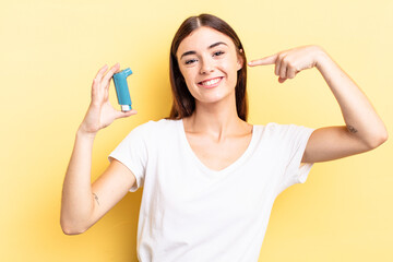 young hispanic woman smiling confidently pointing to own broad smile. asthma concept