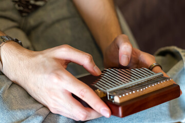 CloBangkok, Thailand-Sep 23, ‎2021:Close up photo of hands of an Asian young  musician playing kalimba