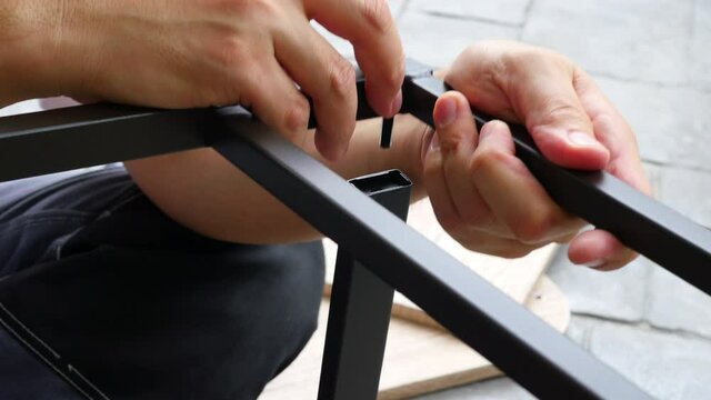 Man doing DIY assembly steel chair frame furniture interia decoration 