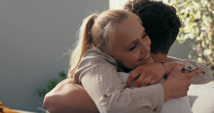A pretty blonde sits on the couch next to her fianc , hugs him longingly, throws herself on his neck, embraces tightly, expresses pride, satisfaction, praises boyfriend, congratulates
