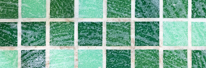 mold on joints between the ceramic tile in bathroom with a cleaning chemical foam. cleaning a black mildew dirt on the seams of mosaic tiles. dirty mould or fungus on wall of the showel room. banner