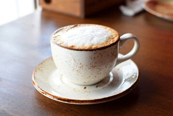 Cappuccino coffee in a beautiful ceramic cup on a wooden table in a cafe. Cup of coffee