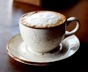 Cappuccino coffee in a beautiful ceramic cup on a wooden table in a cafe. Cup of coffee