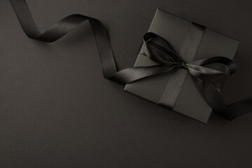 Top view photo of black gift box with black ribbon bow on isolated black background with empty space - Powered by Adobe