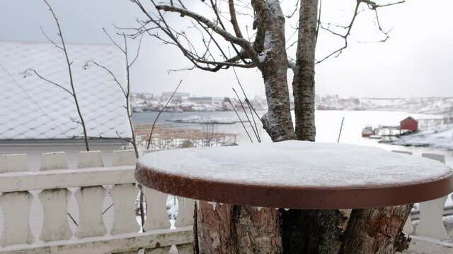 Wooden table with snow covered on outside in snowing day