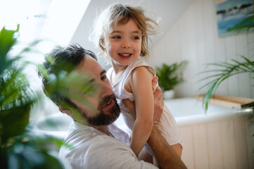 Mature father with small daughter indoors in bathroom at home.