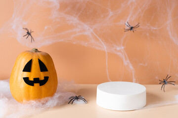 White podium with fun scary face pumpkin. Orange background for branding and packaging presentation