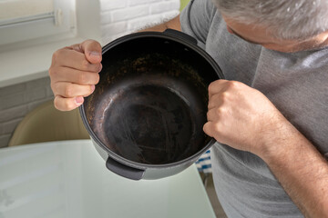 a man holding a non-stick multicooker bowl with a damaged coating