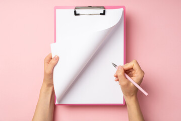 First person top view photo of female hands with pink clipboard holding pen and turning page on...