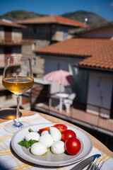 Cheese collection, white balls of Italian soft cheese mozzarella served with fresh tomatoes and basil and white wine