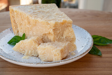 Cheese collection, piece of matured cow cheese pasmesan parmigiano reggiano and Italian houses on background