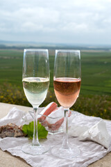 Glasses of white and rose brut champagne wine and examples of vineyard soils, white chalk stones and firestones and view on grand cru vineyards of  Montagne de Reims near Verzenay, Champagne, France