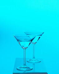Two martini glasses transparent agains colorful background yellow red blue
green 