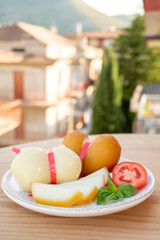 Cheese collection, variety of Italian cow milk cheese scamorza with Italian houses on background