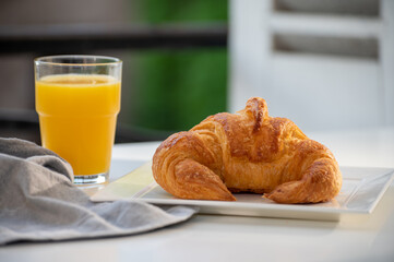 French breakfast, fresh baked croissant buttery pastry served with orange juice and old french houses on background