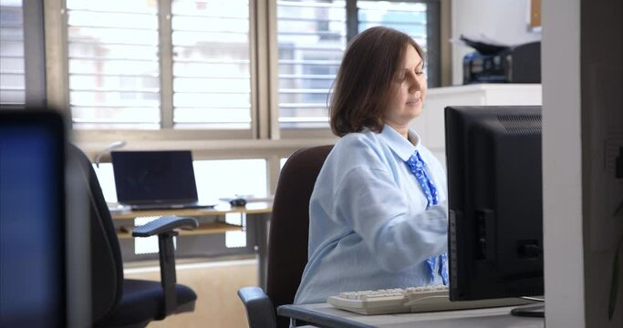 a pregnant woman works in the office at the computer and then takes out the food she brought with her and starts eating during the break.