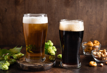 different sorts of craft beer in frosty glasses and snacks on a dark rustic table. Beer brewery concept. copy space