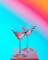 Two martini glasses transparent agains colorful background yellow red blue
green 