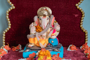 Idol of Lord Ganesh of a shadu clay a Hindu Religion God on the occasion of 'ganesh chaturthi' in India with flowers and decoration.
