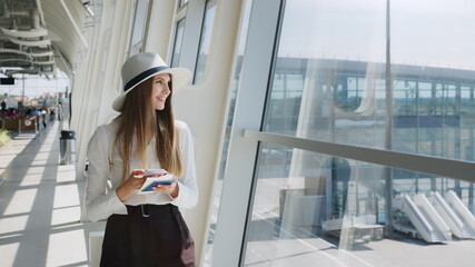 Elegant beautiful business girl holding travel tickets and using phone, happy girl looking at...
