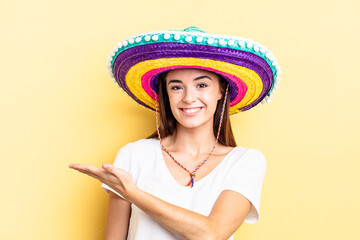 young hispanic woman smiling cheerfully, feeling happy and showing a concept. mexican hat concept - obrazy, fototapety, plakaty