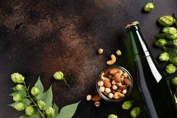 fresh beer bottle, snacks and green hops on grunge background. Free space for text. Top view