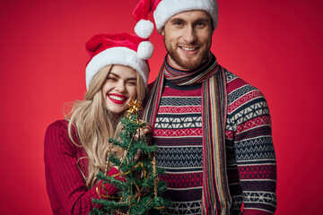 cute young couple holding christmas tree toys decoration red background
