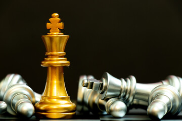 Gold king chess piece win over lying down silver team on black background