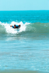 Surfer mężczyzna łapiący falę na desce na tle niebieskiego oceanu i błękitnego nieba. - obrazy, fototapety, plakaty
