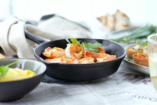 Fried shrimps prawns in a pan and croustades served on a white brown boards