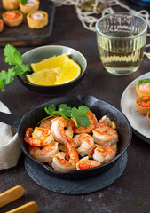 Fried shrimps prawns in a pan and croustades served on a white brown boards