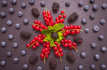 branches of red currants, mint leaves in the middle, blackberries and blueberries