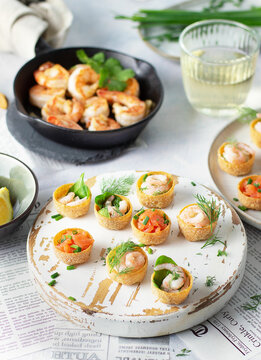 Fried shrimps prawns in a pan and croustades served on a white brown boards