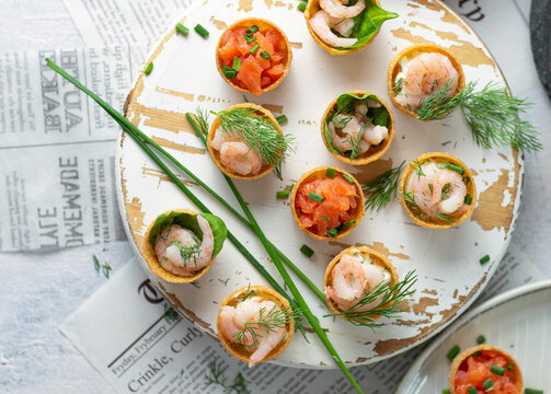 Fried shrimps prawns in a pan and croustades served on a white brown boards