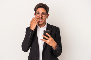Young mixed race business man holding mobile phone isolated on white background biting fingernails, nervous and very anxious.