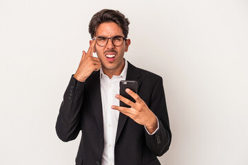 Young mixed race business man holding mobile phone isolated on white background showing a disappointment gesture with forefinger.