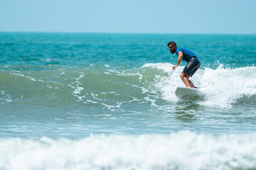 Mężczyzna surfer płynący na fali na tle błękitnego oceanu i nieba. © insomniafoto