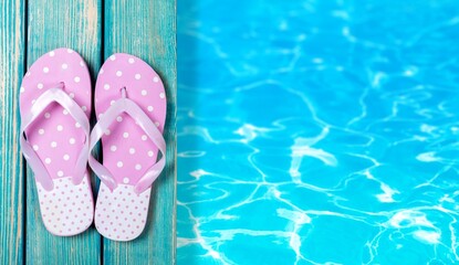Colored flip flops sitting on the edge of a swimming pool.