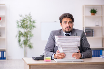 Young male employee and too much work in the office