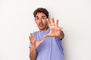 Young mixed race man isolated on white background being shocked due to an imminent danger